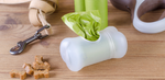 Close-up of dog walking essentials: a leash, a roll of green waste bags in a dispenser, a retractable leash, and a pile of bone-shaped treats on a wooden surface.
